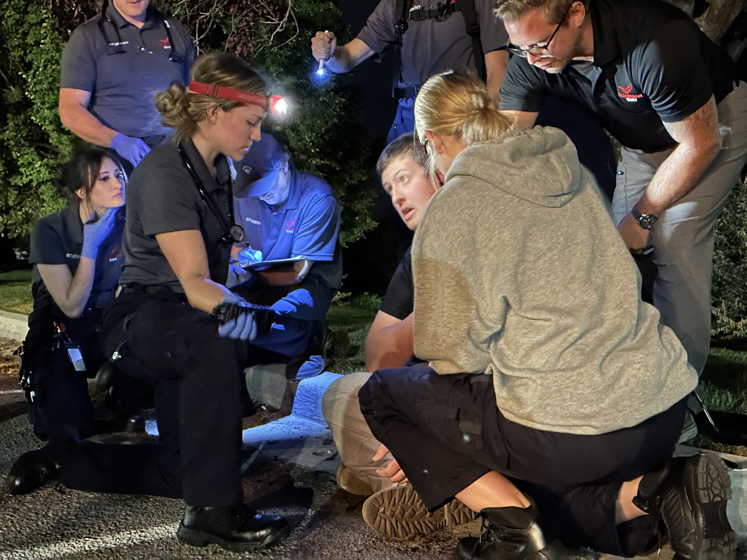 Guardian EMT students gathered around the training ambulance at night